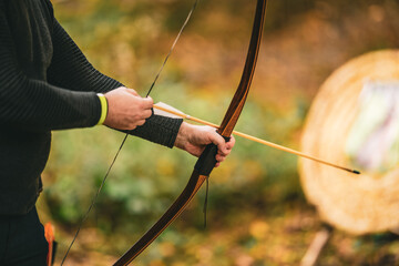 A man is holding a bow and arrow, preparing to shoot at a target