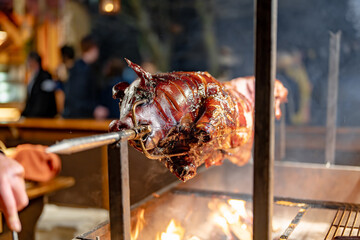 A person is cooking a pork roast on a spit