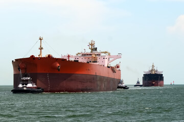 Massive Cargo Ships Navigated by Tugboats in Open Waters