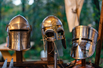 Three metal helmets are displayed on a wooden stand