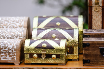 Three wooden chests with gold accents sit on a table