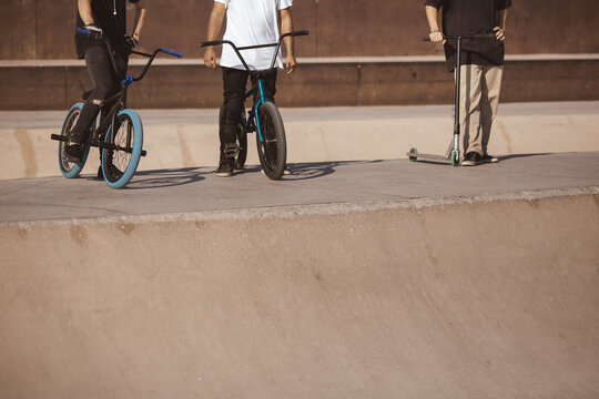 Close-up of two BMX riders and a scooter enthusiast standing at a skatepark, showcasing urban sports culture. Perfect for youth, sport, and active lifestyle themes. 