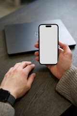 Smartphone Mockup in a mans hand on a wooden office desk