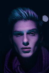 Close-up portrait of a young man with sharp facial features illuminated by dramatic neon purple light, conveying a moody and stylish concept perfect for creative projects.