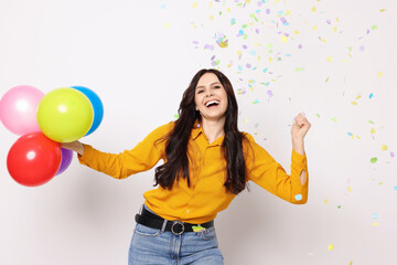Fototapeta premium Happy woman with colorful balloons under falling confetti on white background. Surprise party