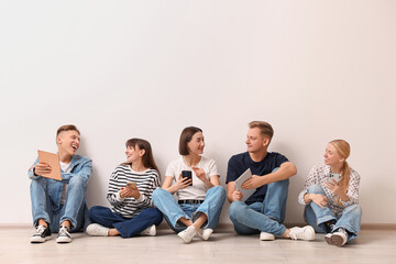 Group of people using different gadgets near white wall indoors. Modern technology