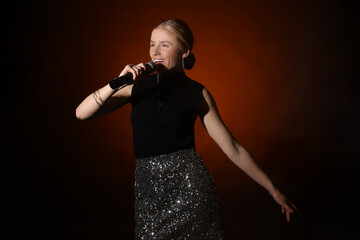 Beautiful singer performing on dark background with color light