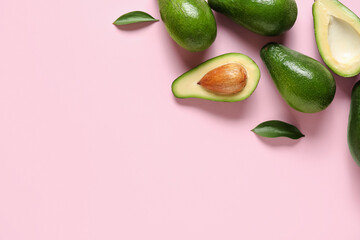 Fresh ripe avocados and leaves on pink background