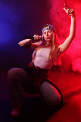 Talented singer performing on dark background with color lights and smoke