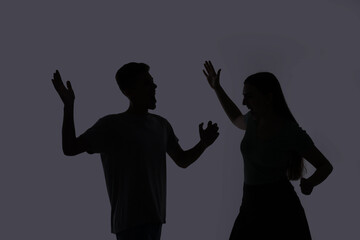 Domestic violence. Silhouette of couple quarreling on grey background