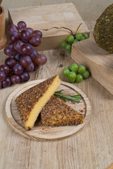 Cheeses in different spices on the table among fruits and greens