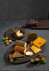 Assortment of cheeses in different spices on the table among fruits and greens