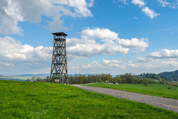 Eliska lookout tower stands tall near Zacler in the Giant Mountains. Surrounded by greenery, the tower offers panoramic views of the picturesque landscape under a blue sky.