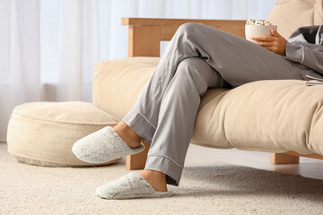 Young woman with cup of cocoa resting on sofa in living room