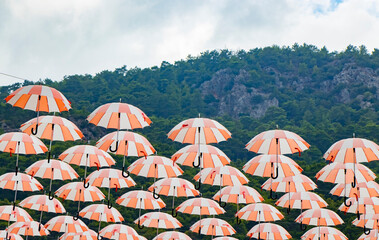 many floating white, orange umbrellas with beautiful mountain landscape in the background in a center of Beldibi, Kemer in Turkey