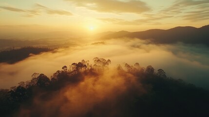 Aerial view of sunrise over misty mountain forest.