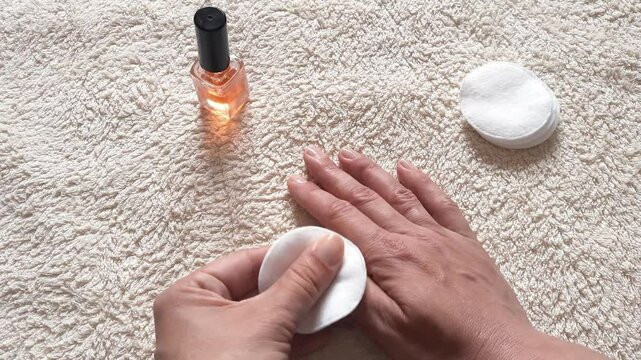 Close-up woman hands rubbing nail care product into her nails in preparation for manicure at home, vitamin oil application for healthy nails, combating brittleness, recovery after gel polish.