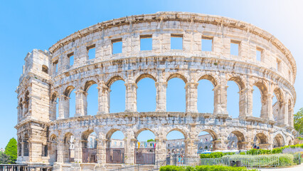 Obraz premium The Roman amphitheatre in Pula, located on the Istria Peninsula, stands as a remarkable symbol of ancient engineering. Visitors explore its impressive arches and stone walls.