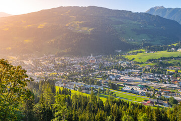 Early morning light illuminates the charming town of Schladming nestled in the Low Tauern mountains. Lush green hills and serene landscapes create a peaceful atmosphere at dawn.