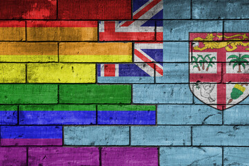 colourful painted big flag of Fiji and rainbow gay pride flag on a massive old brick wall background. concept