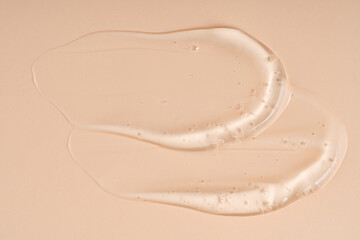 Fototapeta premium Squeezed cosmetic clear cream gel texture Isolated on beige background. Close up transparent serum drop smear