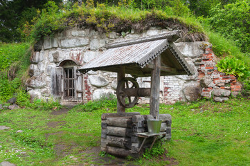Old wooden draw-well and stone cellar in botanical garden, Big Solovetsky Island, Russia