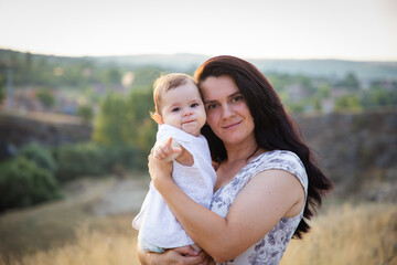 happy young mother with kid in summer at sunset