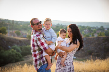 Fototapeta premium happy young family of four in summer at sunset