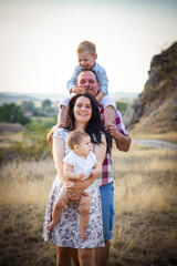 happy young family of four in summer at sunset