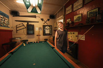 Teenage male playing 8 ball pool on billiard table in Australian pub