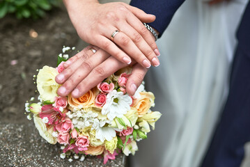 Closeup of wedding couple hands with rings on bouquet, showing love, commitment, floral elegance, togetherness, romance, matrimonial unity concept