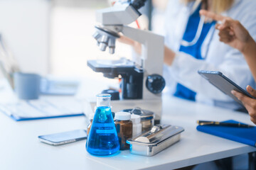 Young African American and Russian woman, both scientists, collaborate to analyze blood samples,...