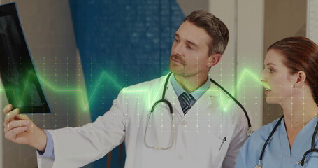 Image of cardiograph over caucasian doctors holding xray
