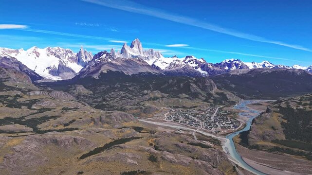 El Chalten Adventure. Witness the majestic peaks of Mount Fitz Roy towering over the charming village of El Chalten, nestled beside the winding Rio de las Vueltas. A true testament to the raw beauty.