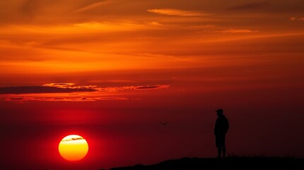 Obraz premium Silhouette of a person against a vibrant sunset, creating a serene and contemplative atmosphere.