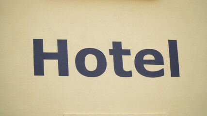 Hotel sign displayed prominently on a light yellow wall, indicating accommodations for travelers in a welcoming location