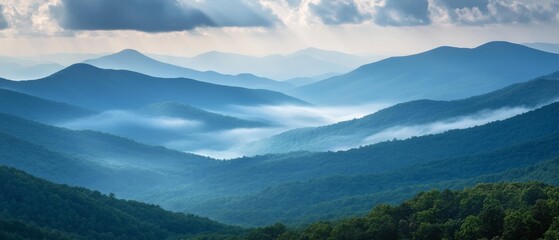 Majestic mountains stretch across a vast landscape, draped in morning mist, under a sky dotted with clouds and gentle sunbeams.
