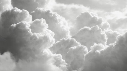 Fluffy clouds of varied shapes and sizes captured in black and white from a low angle, evoking a serene atmosphere.