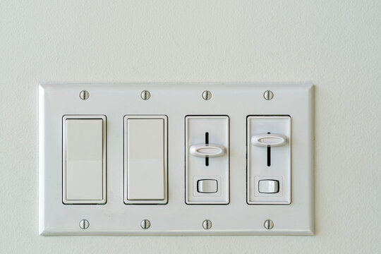 A fixture of mixed rocker switches and light dimmers on a white wall
