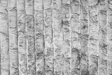 The background in the image appears to be a textured stone or concrete wall with vertical grooves. This surface could represent a natural stone finish or a carved concrete design. High quality photo