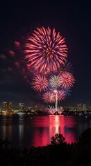 Fototapeta premium Vibrant fireworks illuminate night sky over cityscape reflected in water