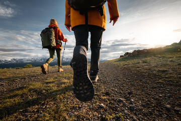 Two young active female hikers tourists girls walks in sunset mountains. Close up photo of woman legs and boots walking in mountains area