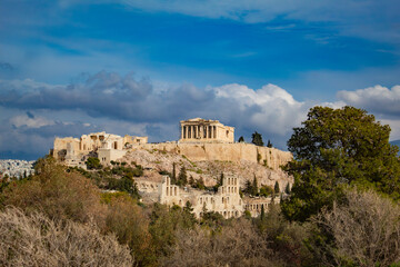Fototapeta premium a beautiful view of the Acropolis of Athens, the Parthenon, against the background of a fabulous sky, among green trees