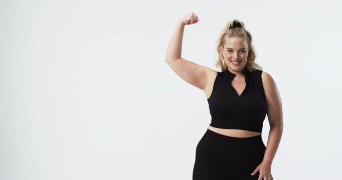 Caucasian plus size woman with light skin, blonde hair, and blue eyes flexing arm and smiling, copy
