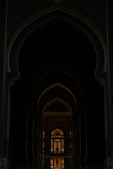 Naklejka premium High definition photograph of a jet black Islamic archway at night. The focus is on intricate detail and deep shadows, with dark gold accents adding subtle