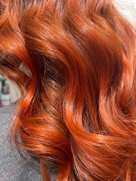 cabello brillante en colores cobrizos, con peinado en ondas suaves.