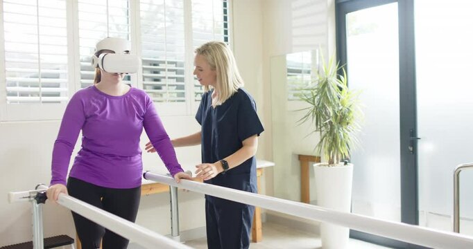 Using VR headset, woman in prosthetic leg walking with therapist on parallel bars