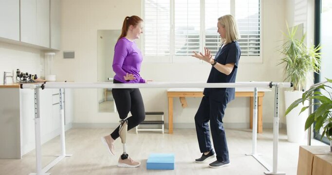 Woman with prosthetic leg practicing walking with therapist on parallel bars