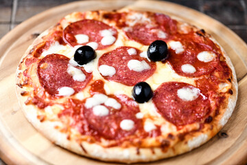 Pizza with salami and mozzarella cheese. Wooden background. Soft focus. Close up.	