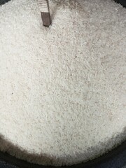 A detailed close-up of uncooked white rice grains in a container with a wooden scoop. Perfect for use in culinary, agriculture, and food-related visuals.